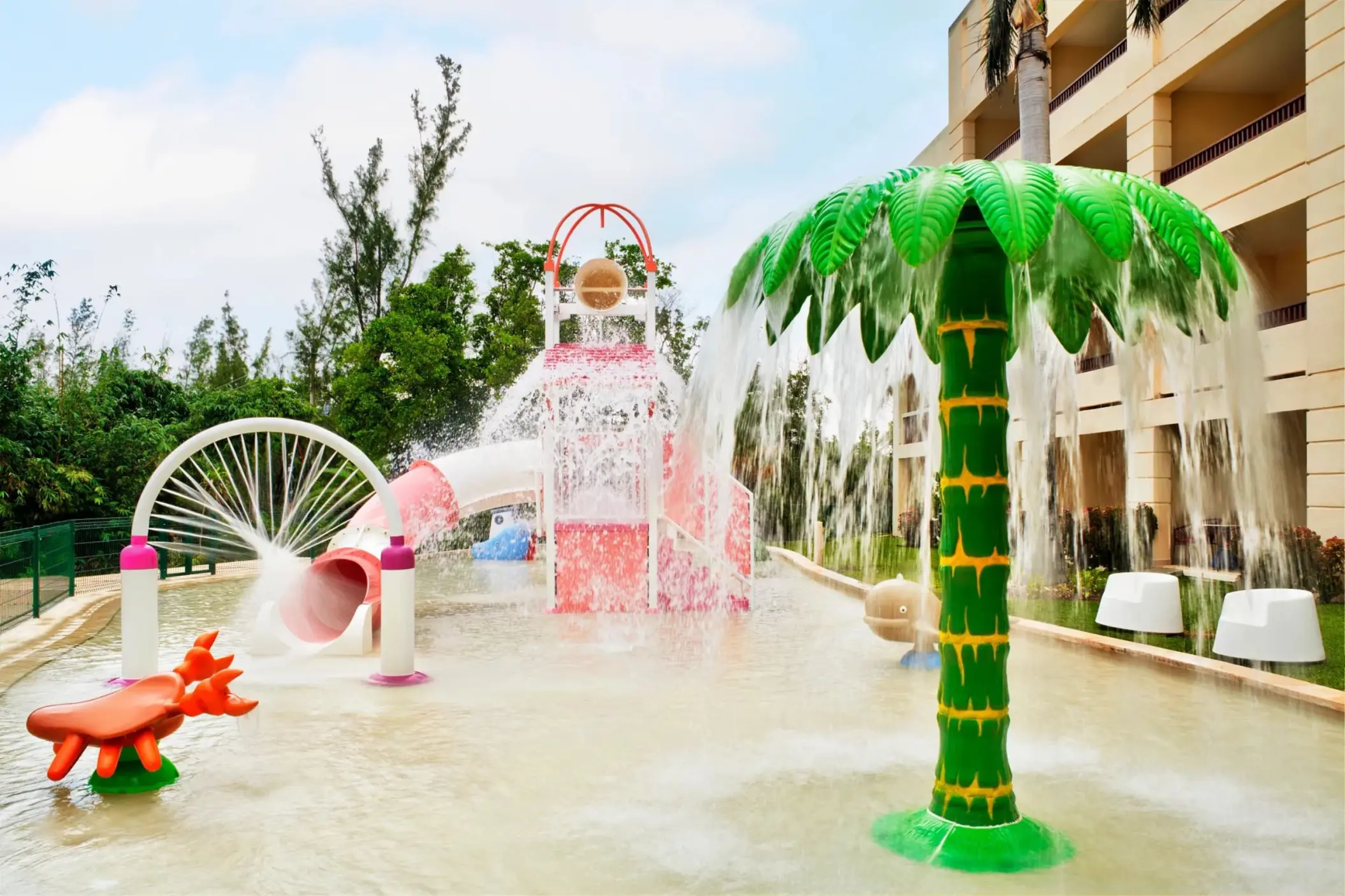 Children's splash park with water slides and a palm tree fountain at Dreams Puerto Morelos, Riviera Maya