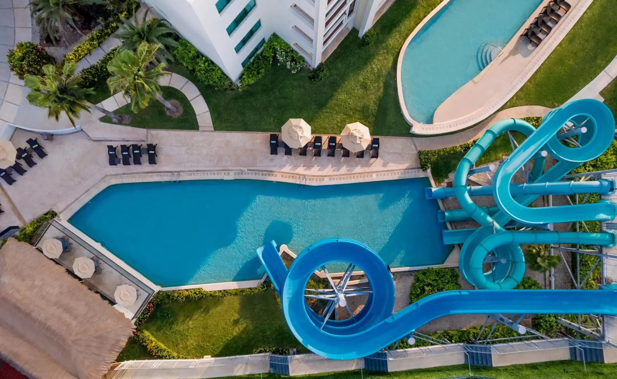 Aerial view of blue waterslides and pools at Dreams Puerto Morelos, Riviera Maya