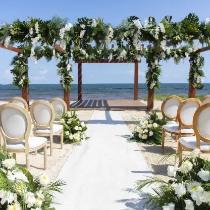 Beachfront wedding ceremony with floral pergola and white aisle at Secrets Riviera Cancun, Riviera Maya