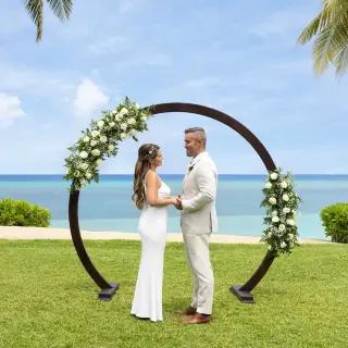 Bride and groom under a circular floral arch at a West Lawn wedding ceremony at Dreams Rose Hall, Montego Bay