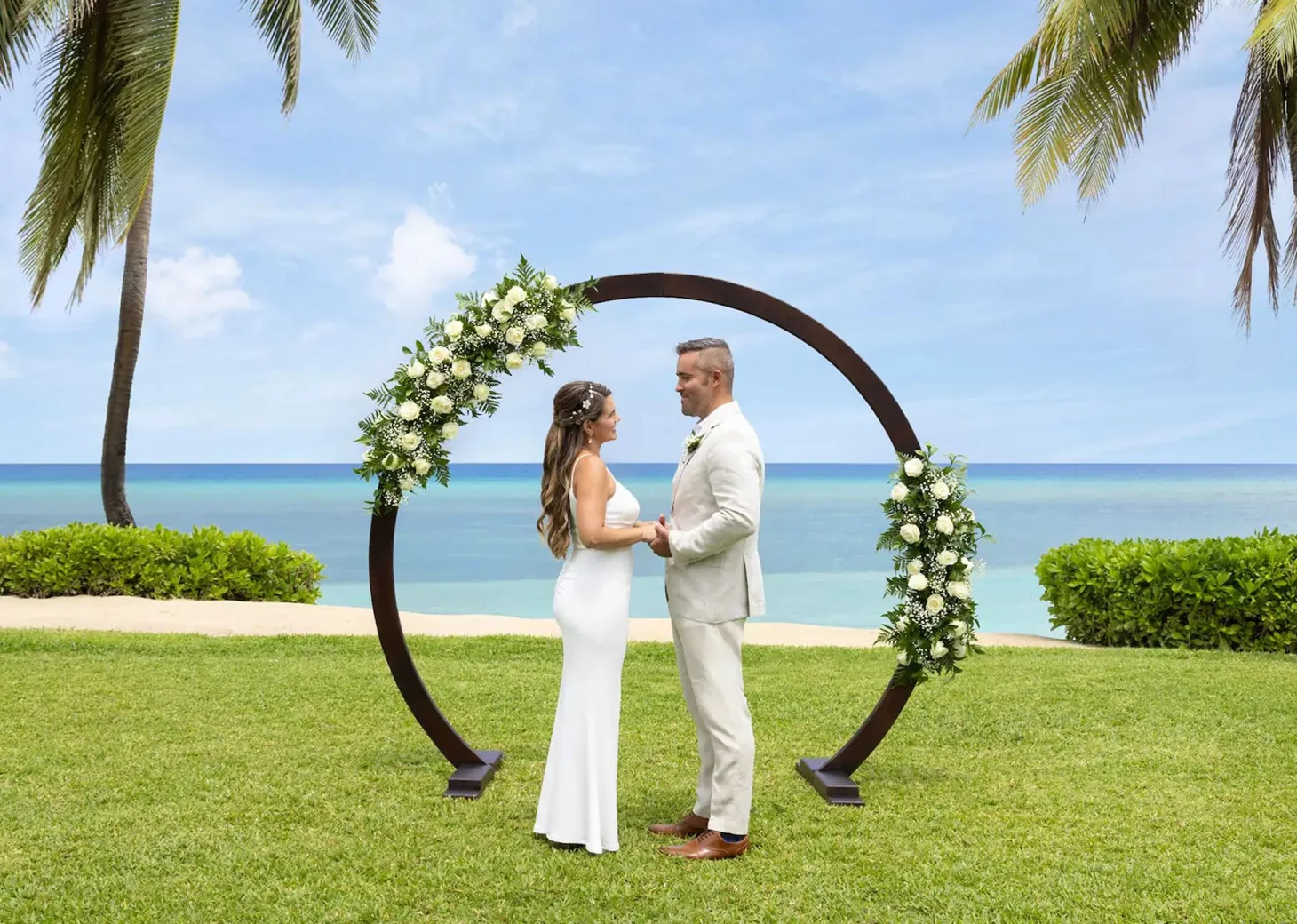 A bride and groom standing at the resort's West Lawn wedding venue with the ocean in the background.