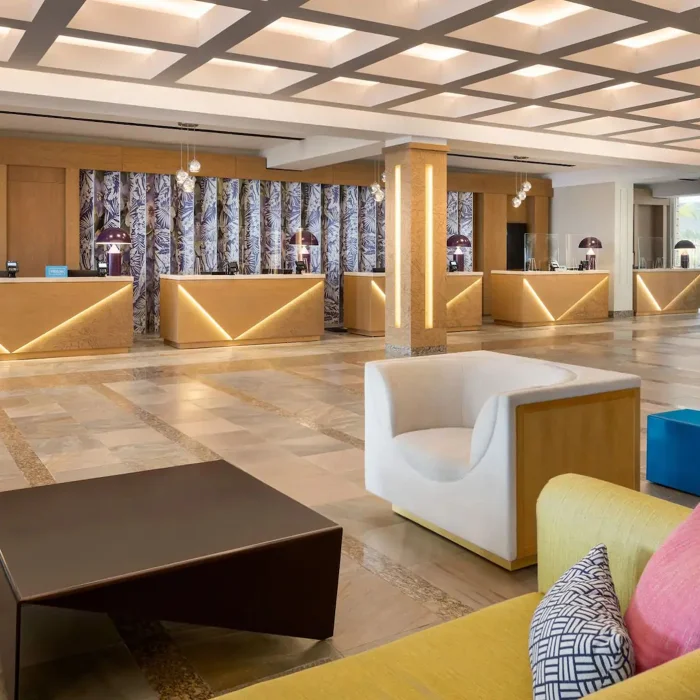 The elegant and modern entrance lobby of Dreams Rose Hall Resort & Spa with stylish furniture and reception desks.