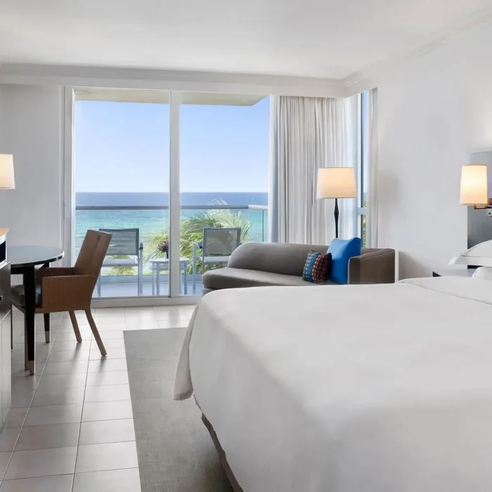The elegant bedroom of an Oceanfront Royal Suite with a king-sized bed and a balcony overlooking the sea.