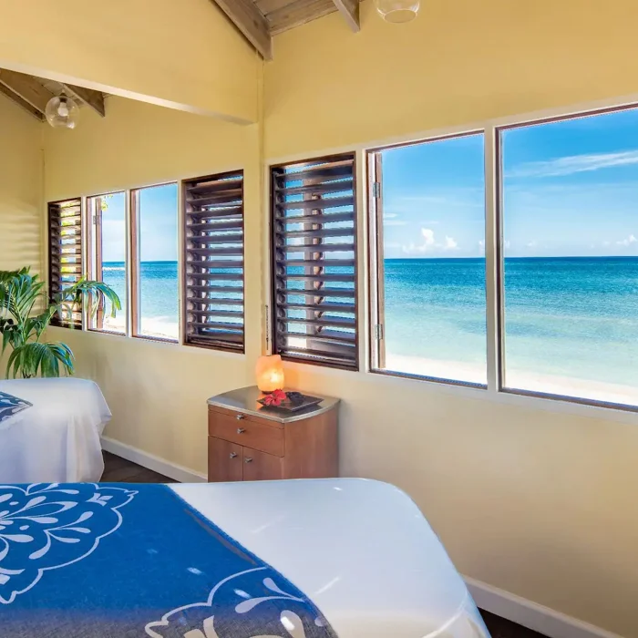 The tranquil interior of the Spa by the Sea, with two massage tables and large windows facing the ocean.