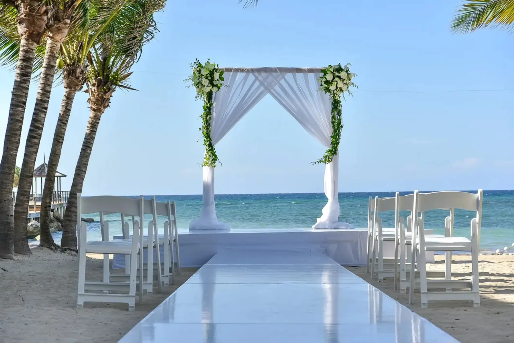 Beachfront wedding ceremony with white draped arch at Dreams Rose Hall, Montego Bay