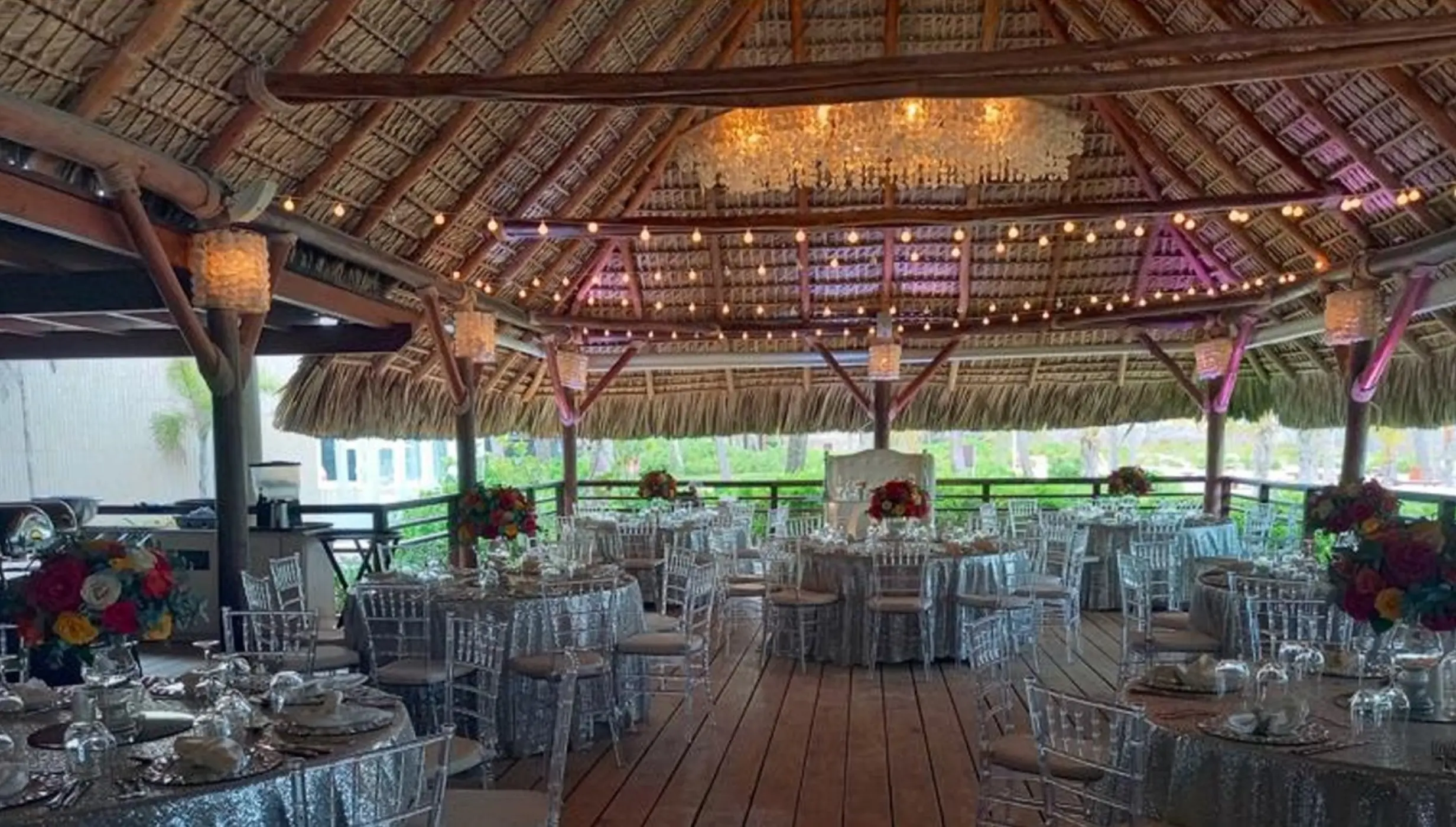 Wedding reception with silver linens under a thatched palapa at Dreams Royal Beach, Punta Cana