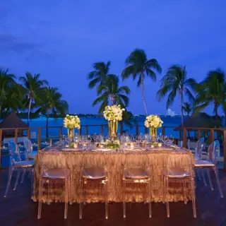 Evening wedding reception setup with clear chairs and floral centerpieces at Dreams Sands Cancun, Cancun