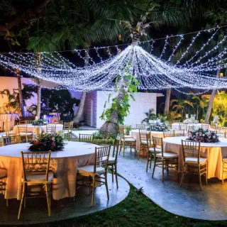 Nighttime wedding reception with string lights and round tables at Dreams Sands Cancun, Cancun