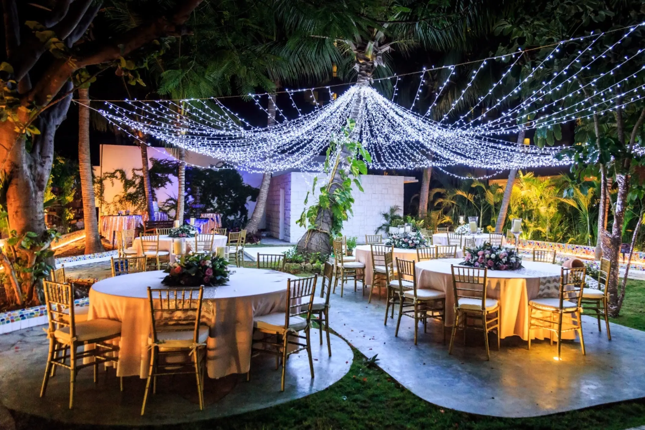 Nighttime wedding reception with string lights and round tables at Dreams Sands Cancun, Cancun