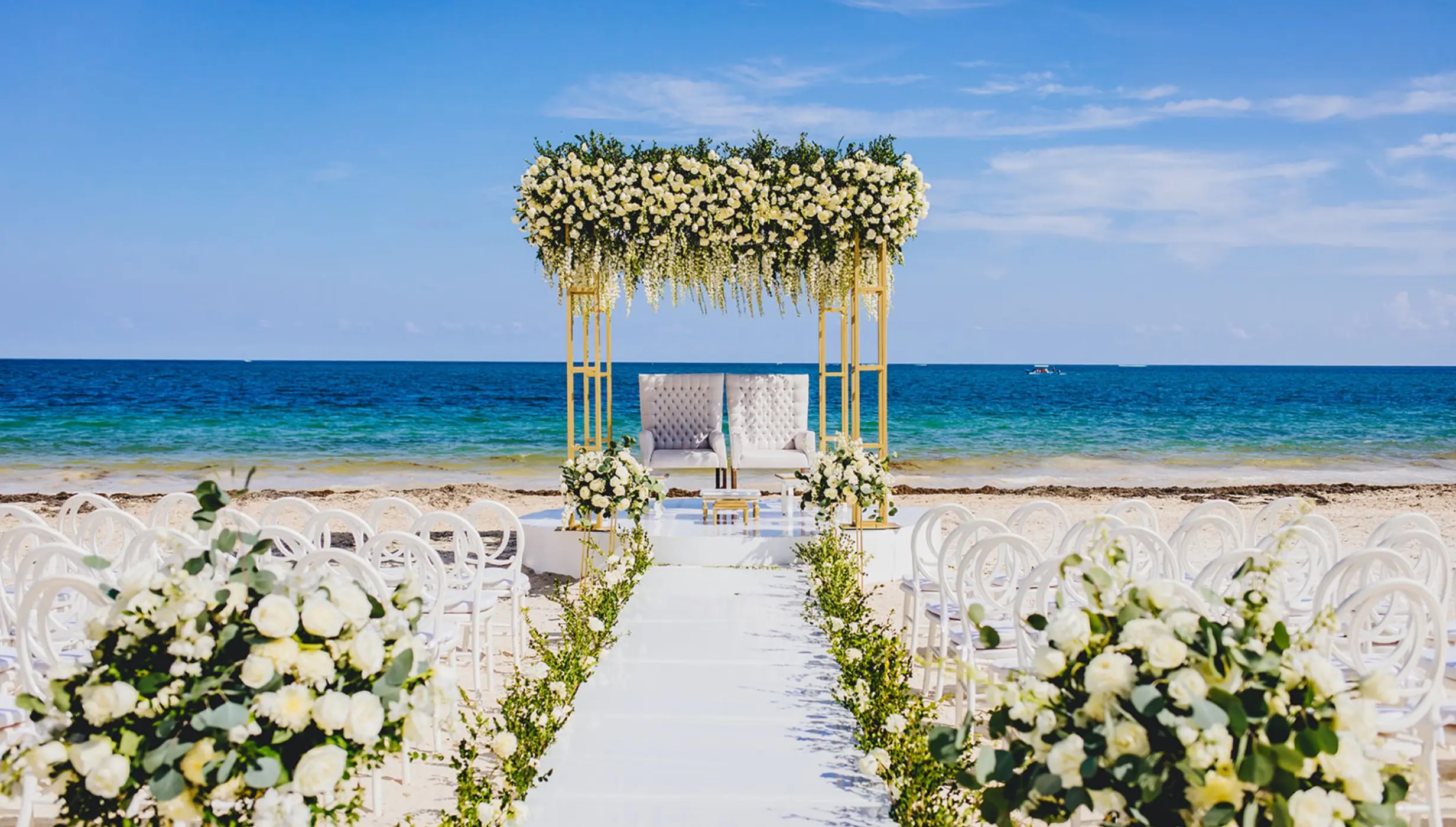Beachfront wedding ceremony setup with white floral arch at Dreams Sapphire, Riviera Maya