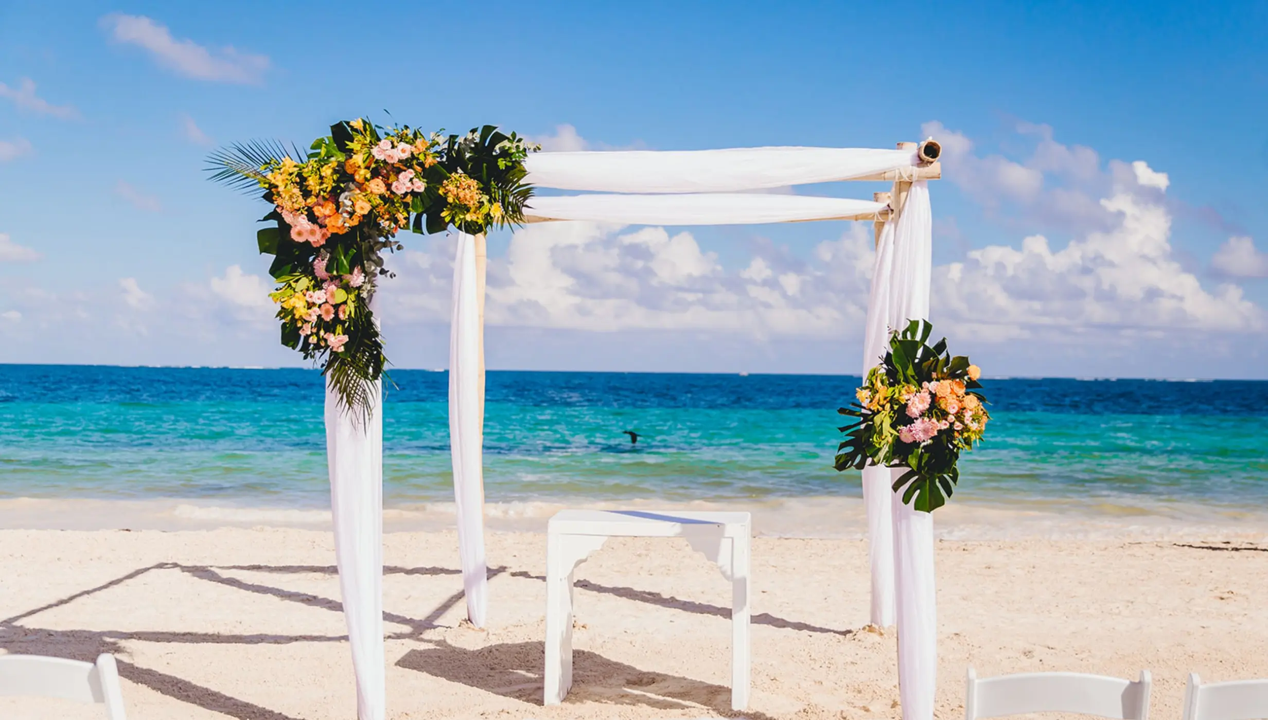 Beachfront wedding ceremony arch with floral arrangements at Dreams Sapphire, Riviera Maya