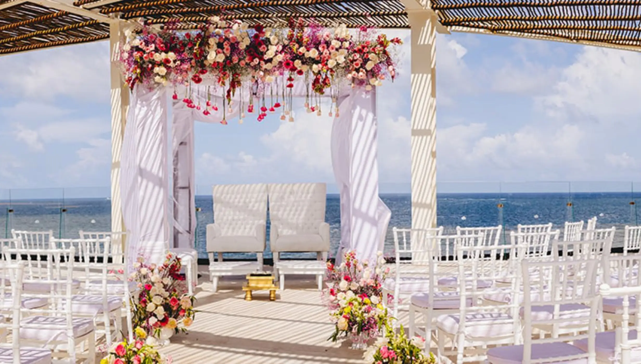 Sky rooftop wedding ceremony with white chairs and floral arch at Dreams Sapphire, Riviera Maya