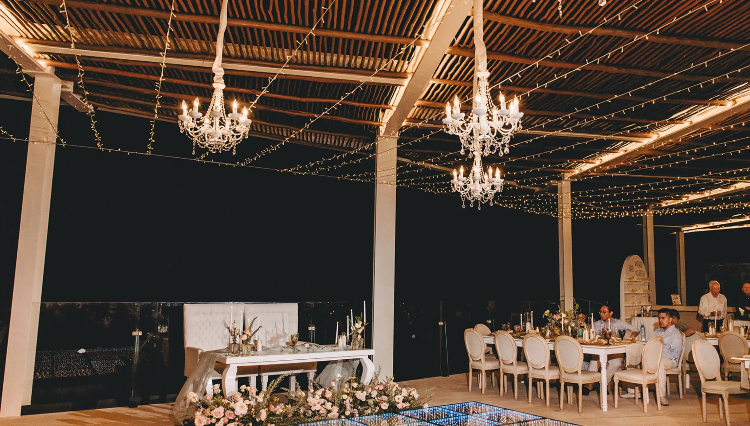 Rooftop wedding reception at night with chandeliers and light-up dance floor at Dreams Sapphire, Riviera Maya