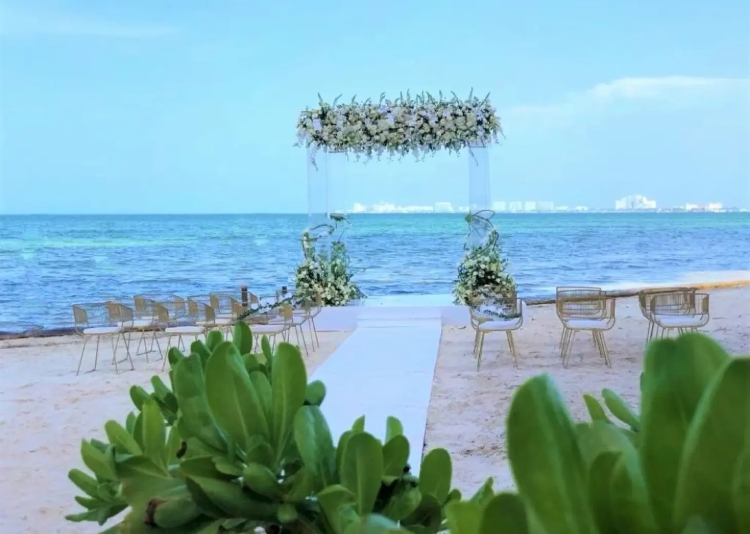 Beachfront wedding ceremony with a floral arch and white aisle at Dreams Vista Cancun