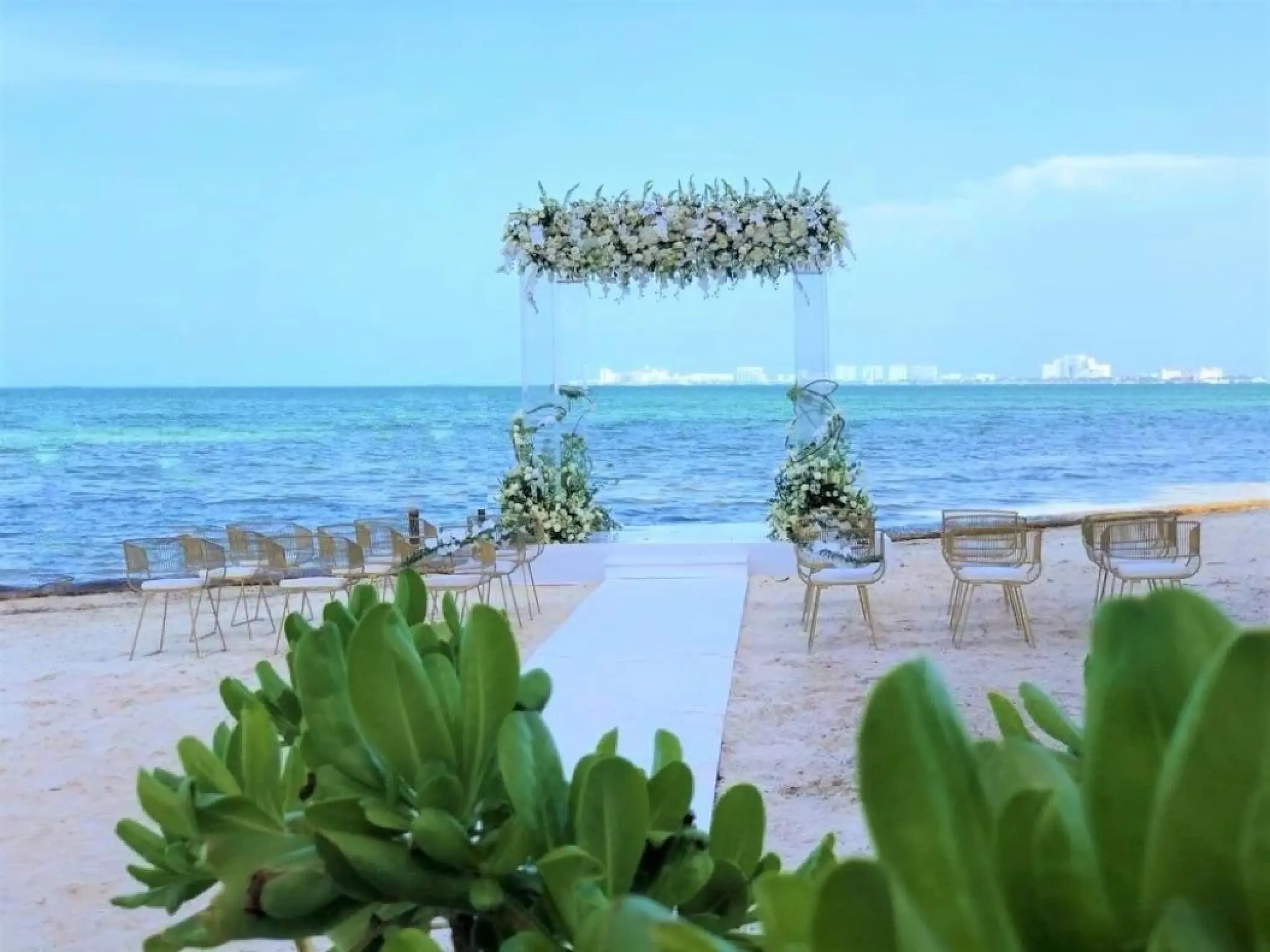 Beachfront wedding ceremony with a floral arch and white aisle at Dreams Vista Cancun