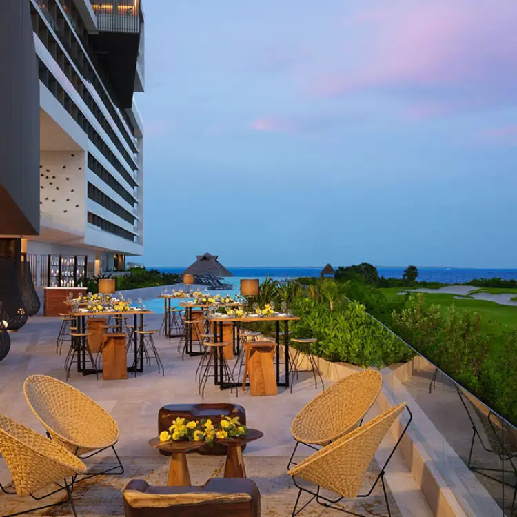 Outdoor terrace with seating and high-top tables overlooking the ocean at Dreams Vista Cancun, Cancun