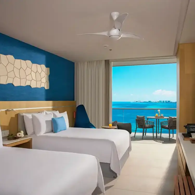 Family suite with two queen beds and a balcony overlooking the ocean at Dreams Vista Cancun