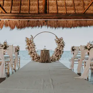 Wedding ceremony with a circular floral arch under a palapa at Dreams Vista Cancun