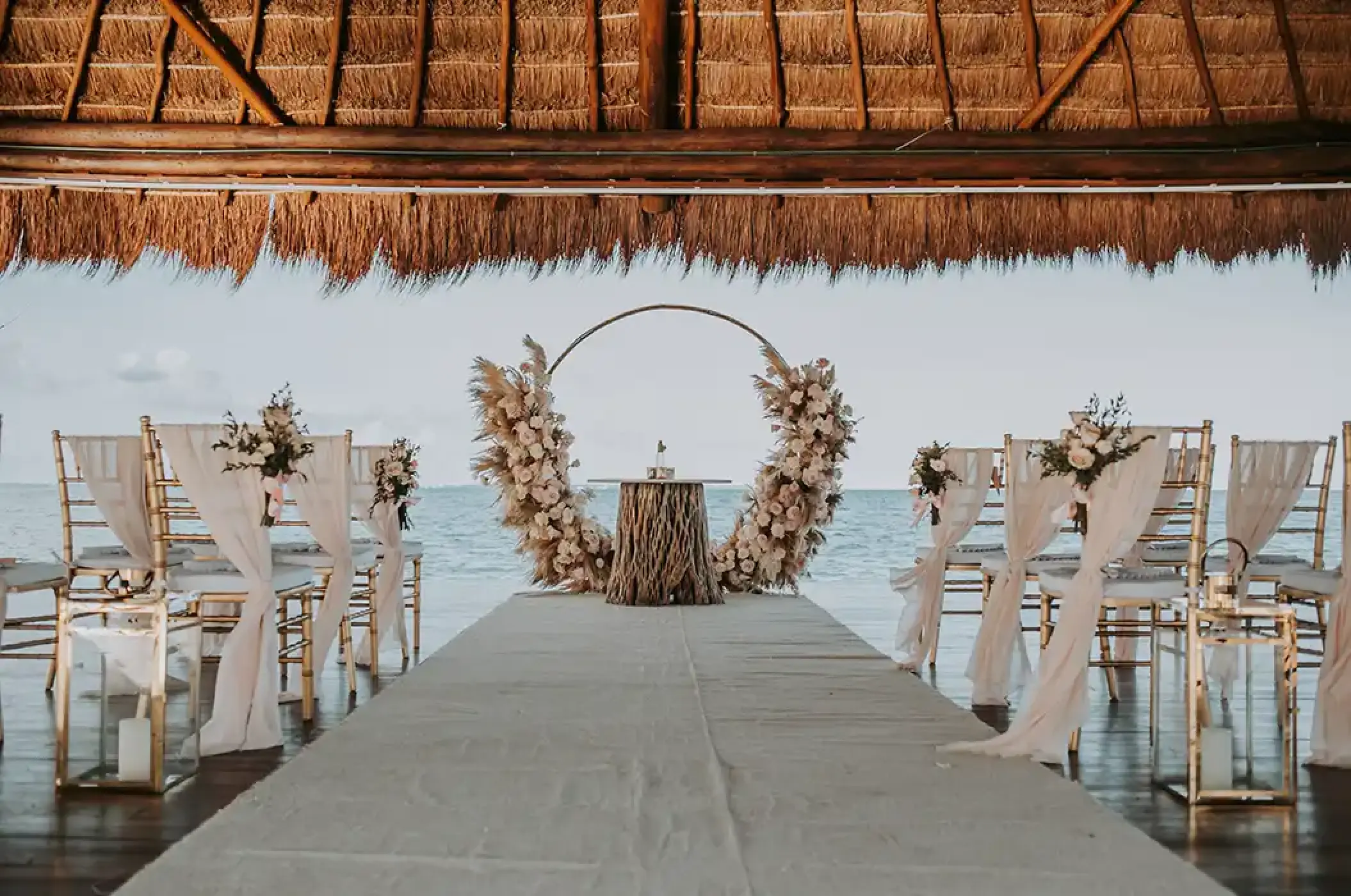 Wedding ceremony with a circular floral arch under a palapa at Dreams Vista Cancun