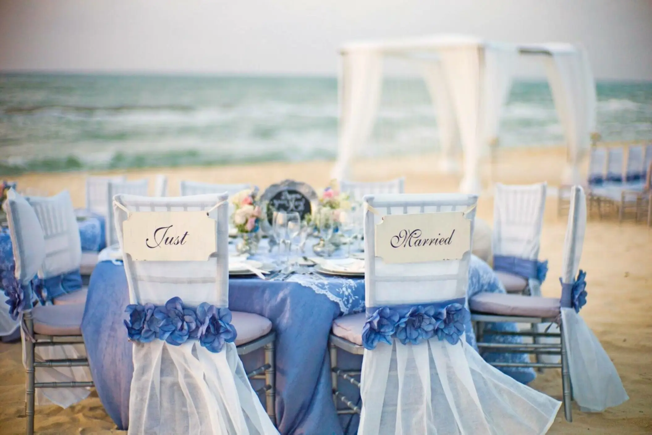 Beachfront wedding reception table with Just Married signs at El Dorado Palafitos, Riviera Maya