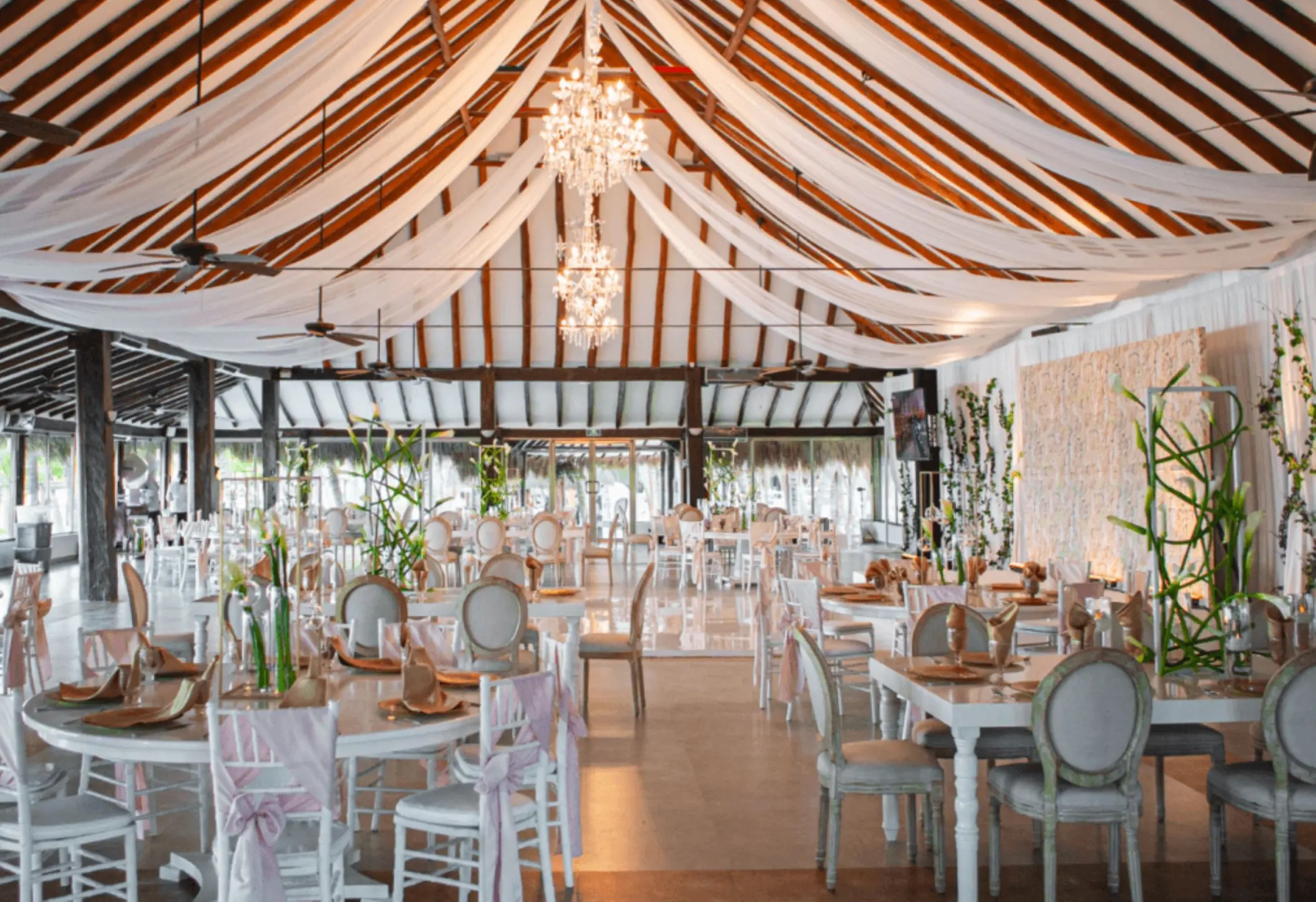 Indoor wedding reception setup with white draping and chandeliers at El Dorado Maroma, Riviera Maya