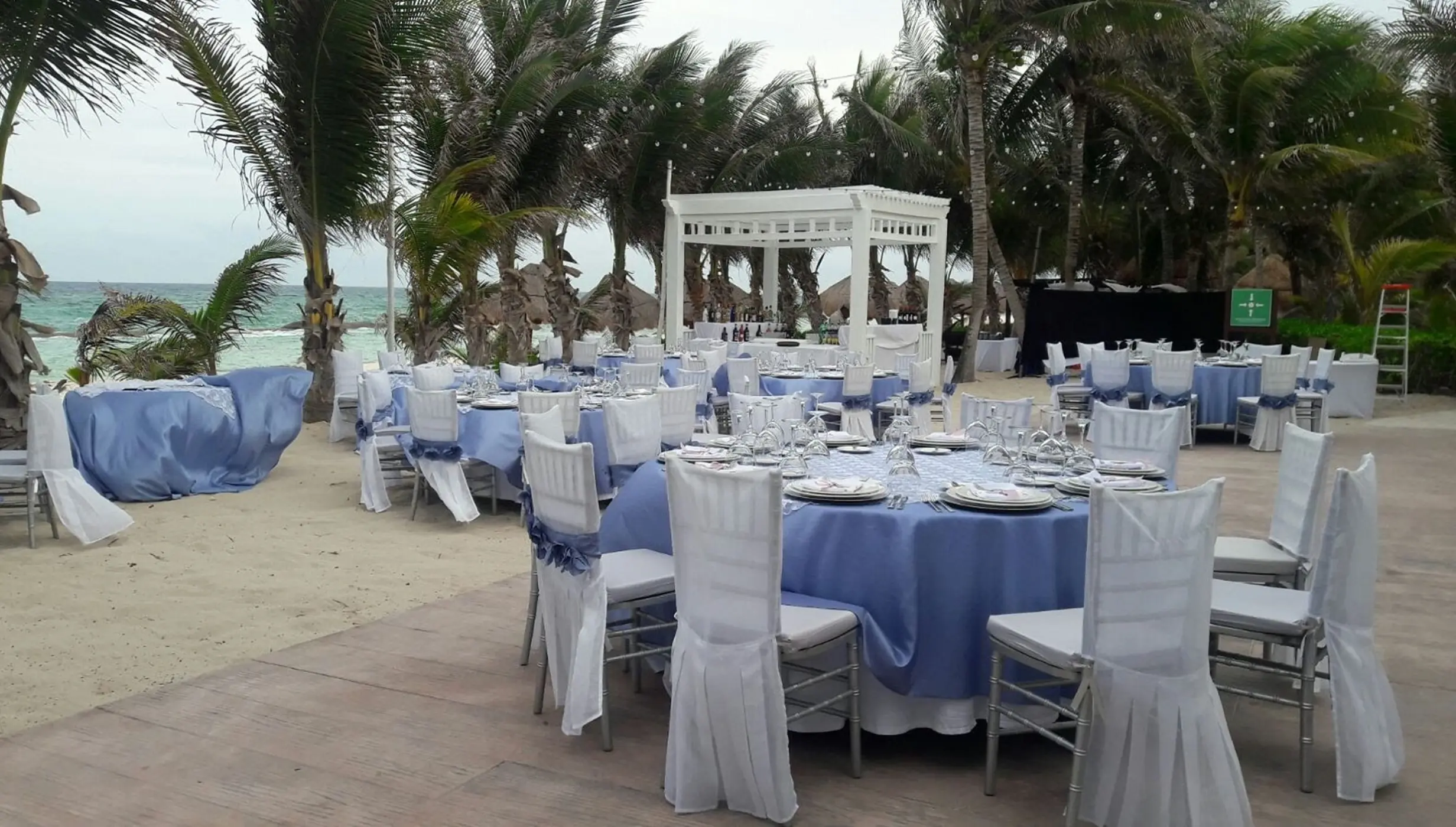 Beachfront wedding reception setup with blue linens and white chair covers at El Dorado Royale, Riviera Maya