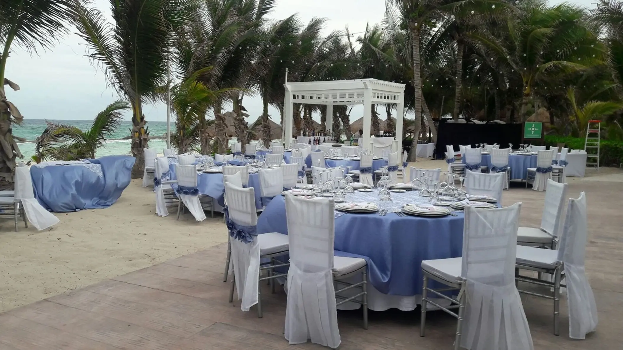 Beachfront wedding reception setup with blue linens and white chair covers at El Dorado Royale, Riviera Maya