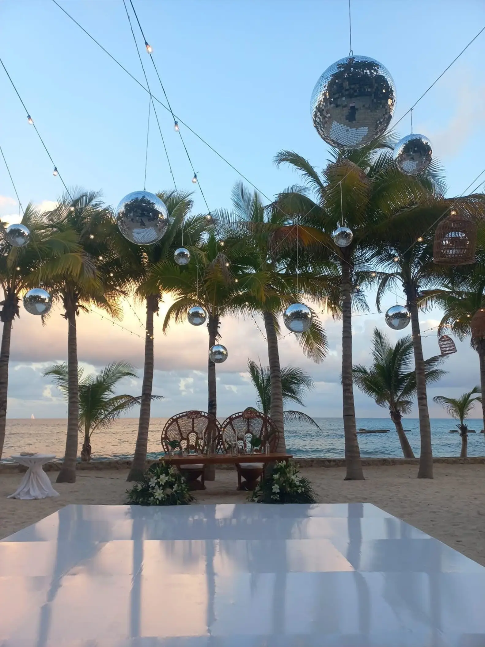 Beachfront wedding reception setup with disco balls and a dance floor at El Dorado Royale, Riviera Maya