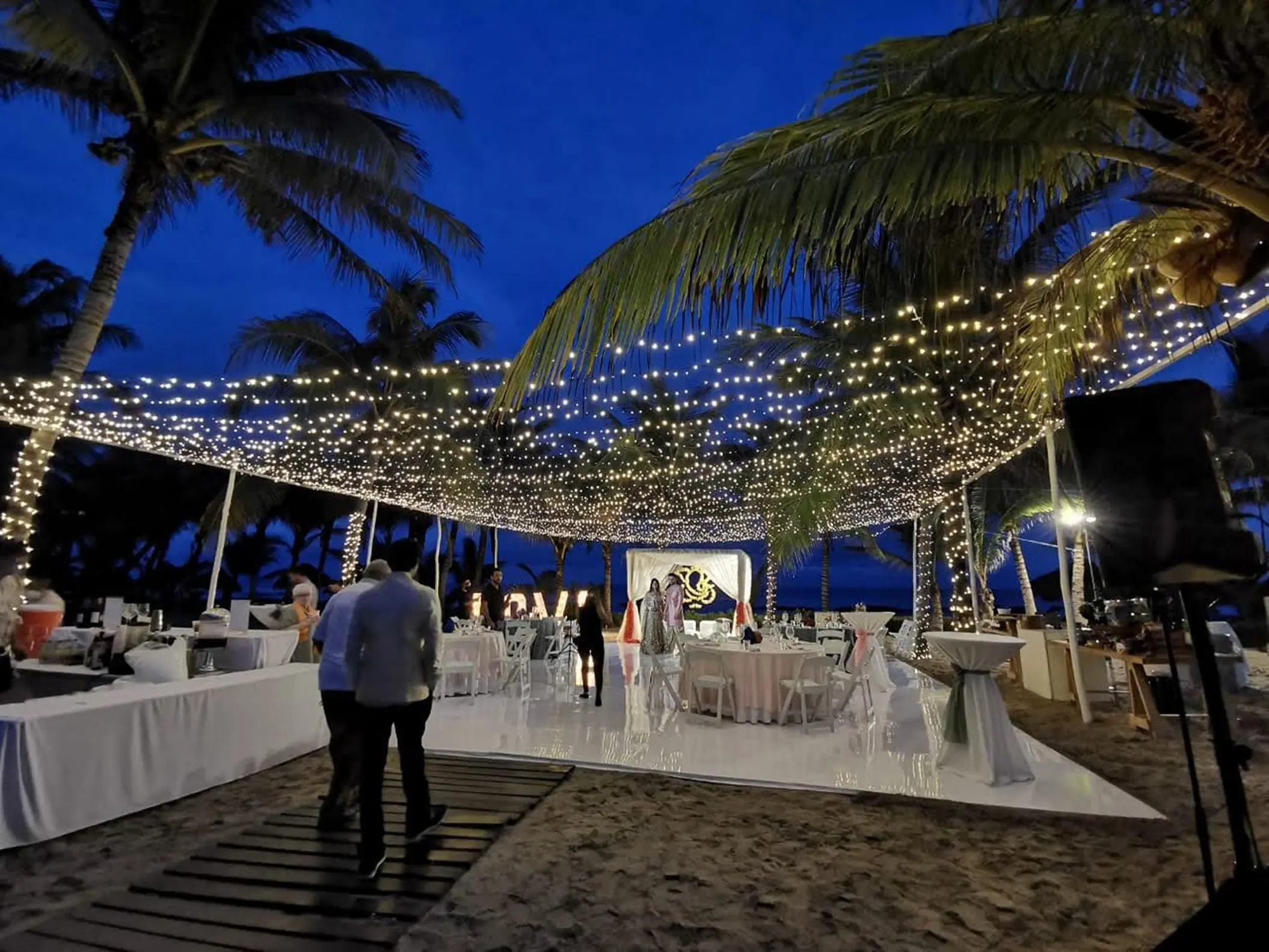Fuentes venue evening reception with fairy lights and white dance floor at El Dorado Royale, Riviera Maya