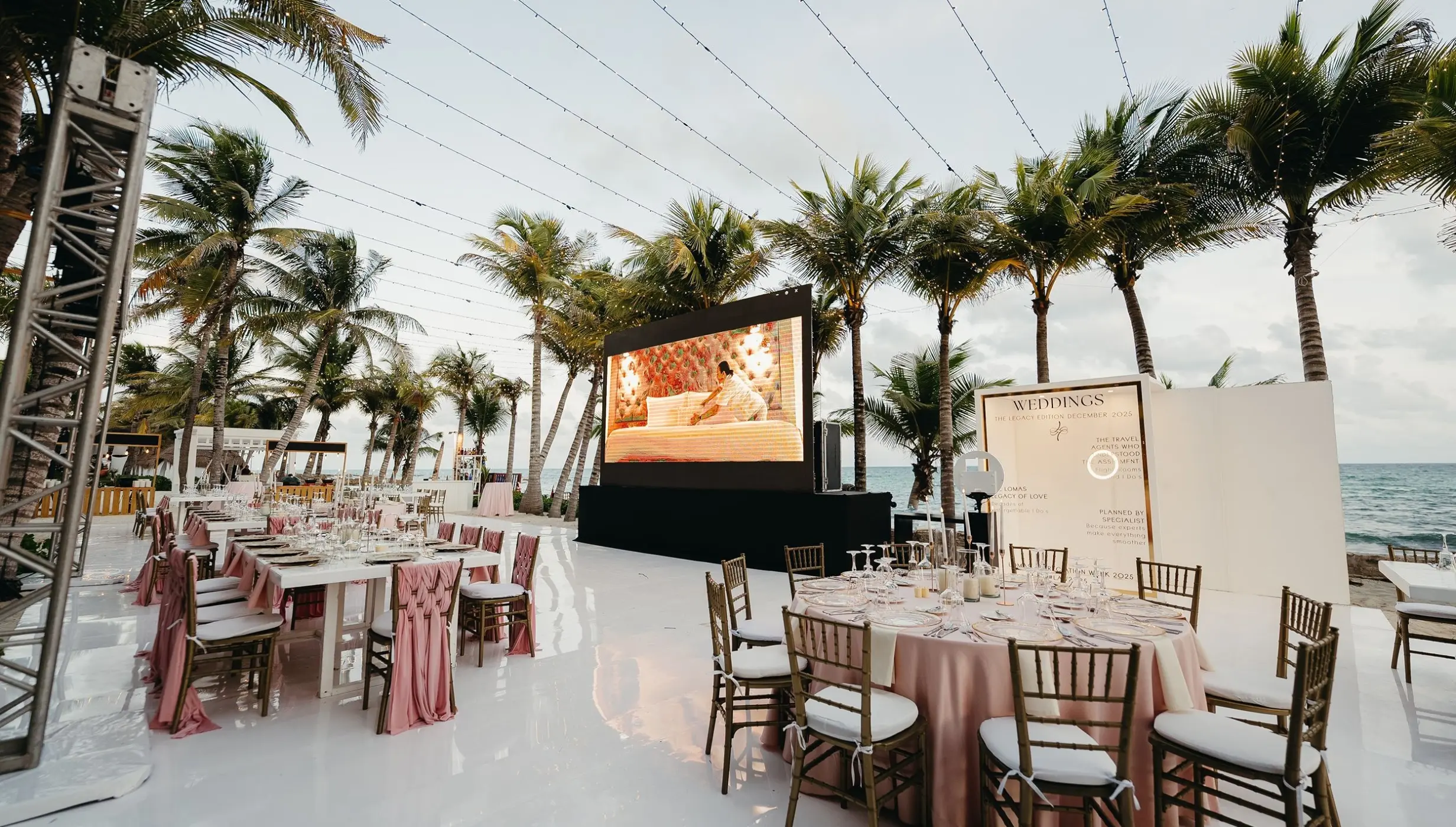 Outdoor wedding reception with large screen and pink decor at El Dorado Royale, Riviera Maya