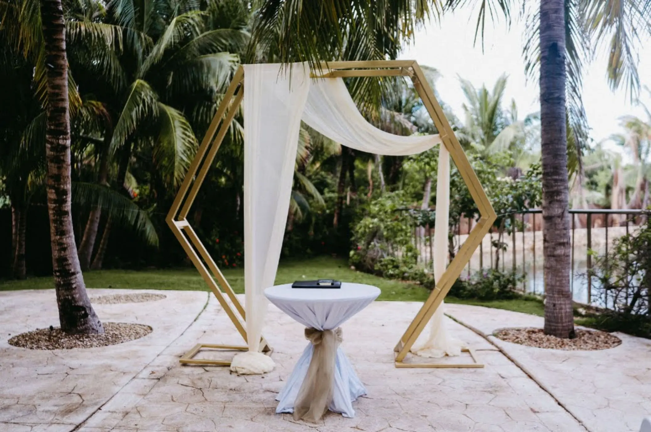 Hexagonal wooden wedding ceremony arch with white draping at El Dorado Royale, Riviera Maya