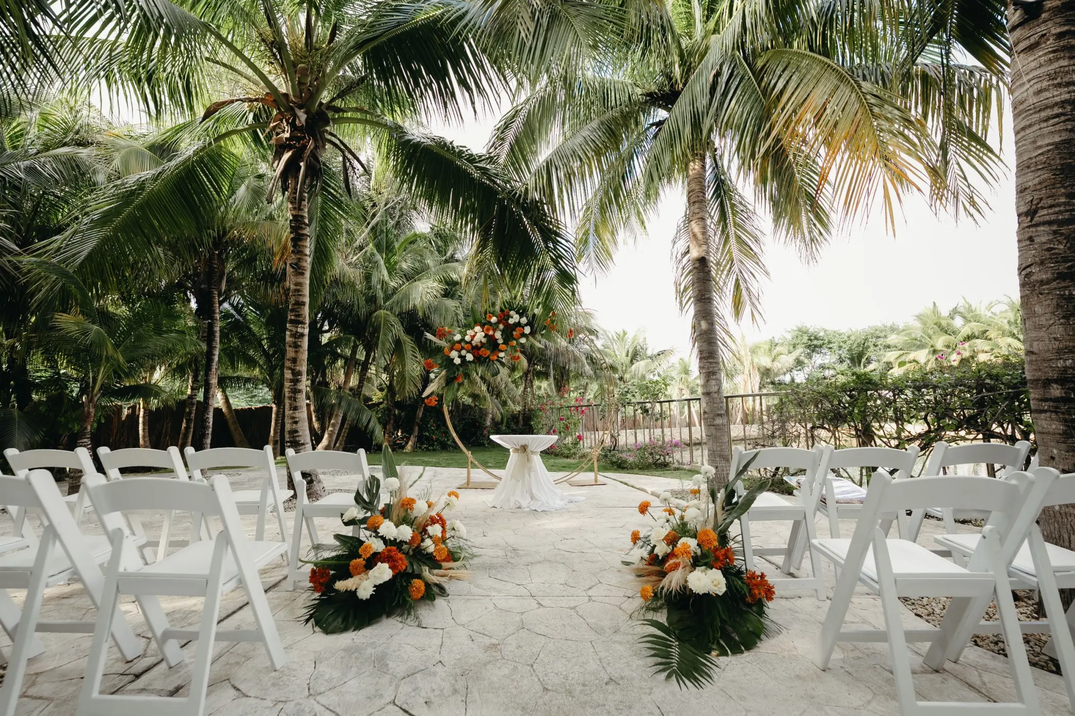 Garden terrace wedding ceremony with white chairs and floral arrangements at El Dorado Royale, Riviera Maya