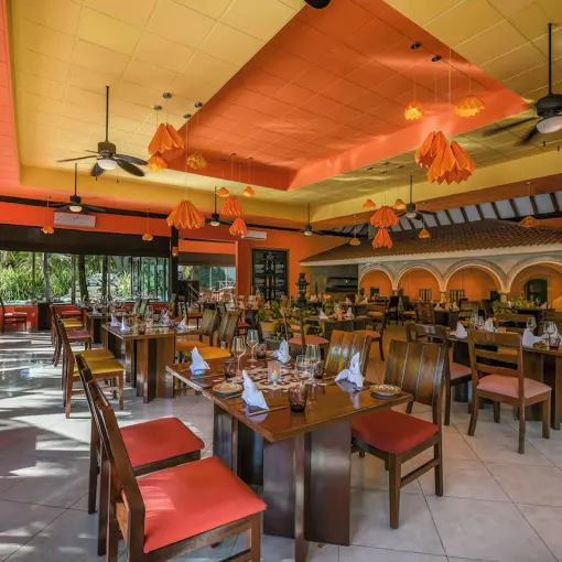 Colorful gourmet restaurant with orange accents and ceiling fans at El Dorado Royale, Riviera Maya