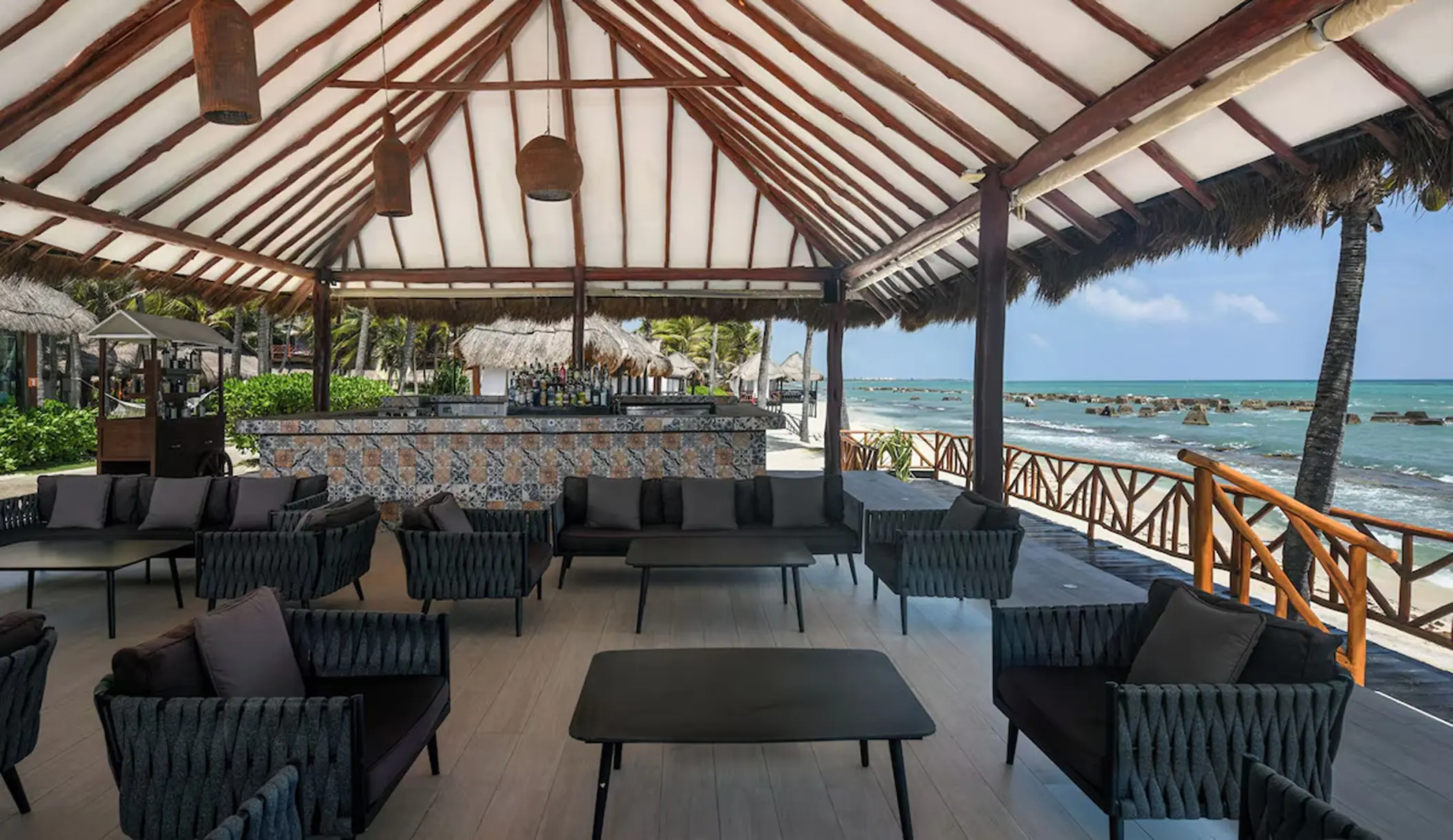 Outdoor lounge and bar under a palapa roof at El Dorado Royale, Riviera Maya