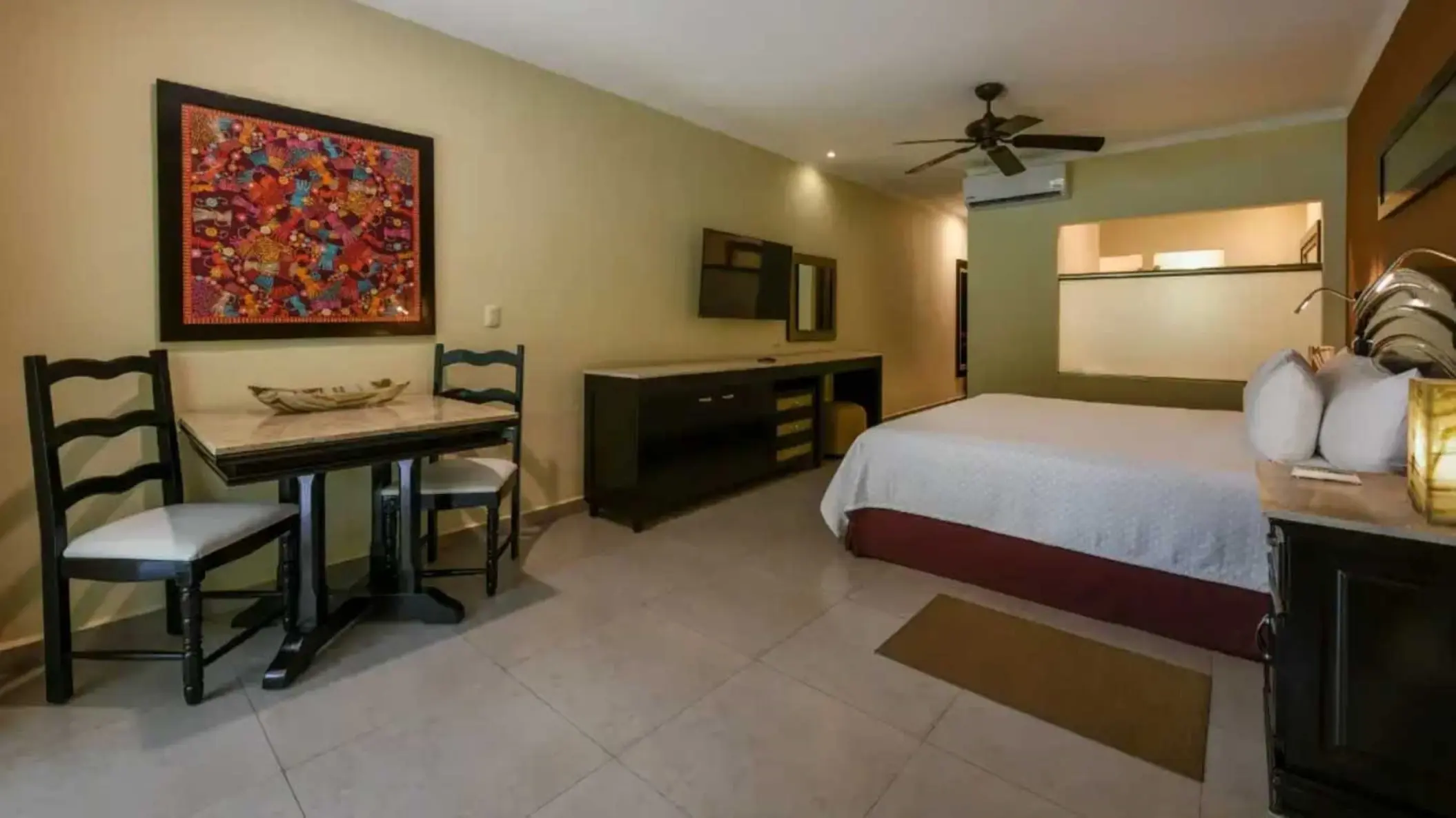 Luxury suite with a king bed and dining area at El Dorado Royale, Riviera Maya