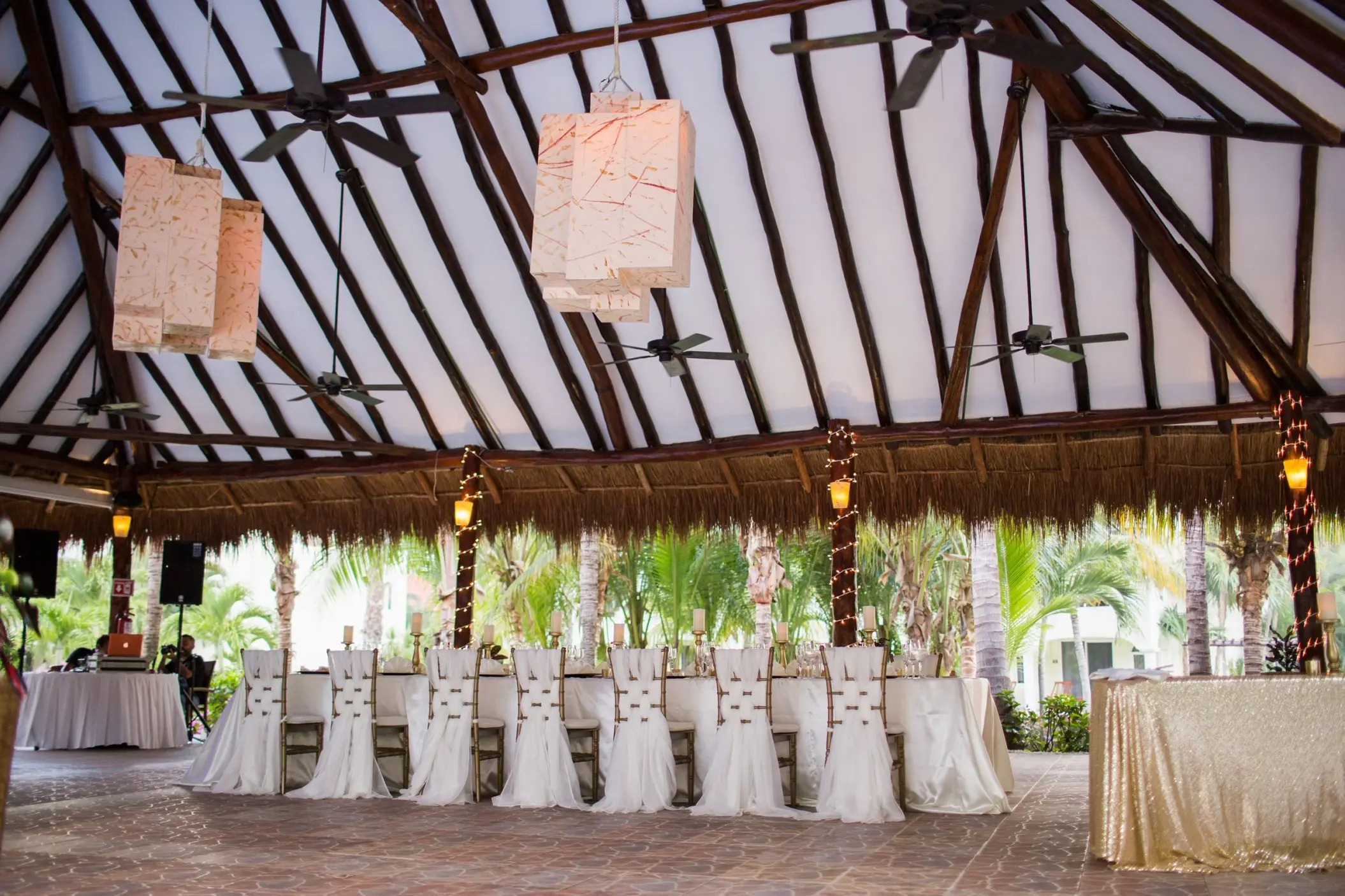 Covered reception terrace with a long dining table under a palapa roof at El Dorado Royale, Riviera Maya