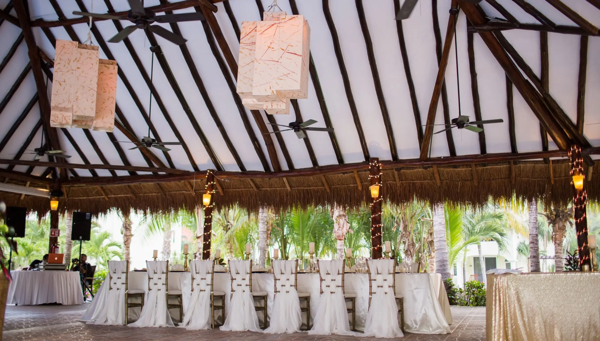 Covered reception terrace with a long dining table under a palapa roof at El Dorado Royale, Riviera Maya