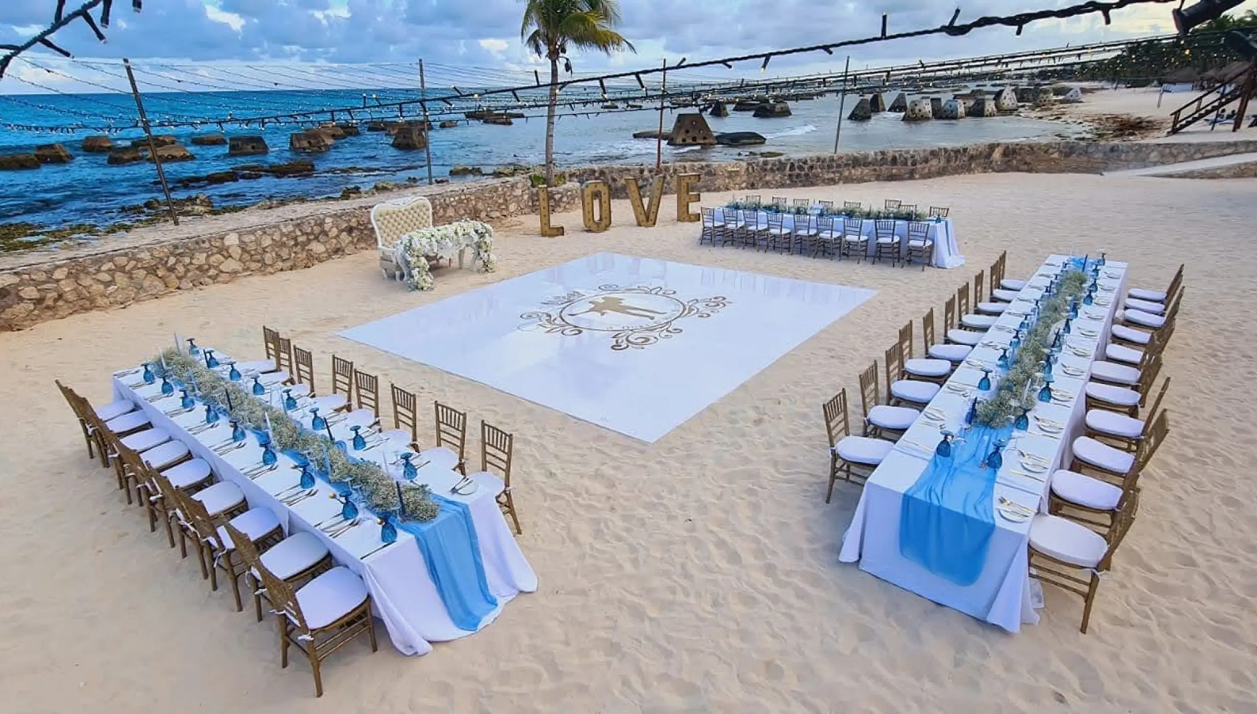 Beachfront wedding reception setup with dance floor and blue table runners at El Dorado Royale, Riviera Maya