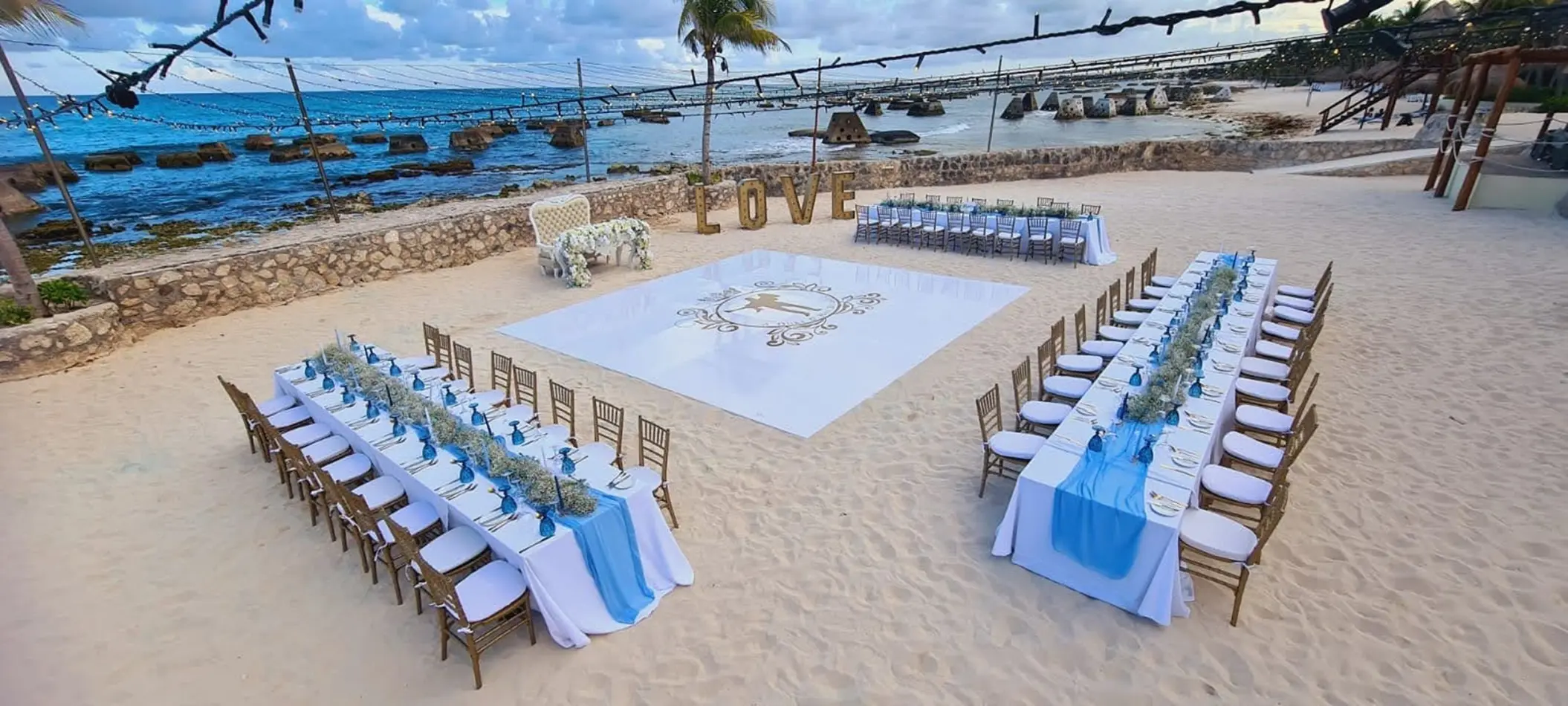Beachfront wedding reception setup with dance floor and blue table runners at El Dorado Royale, Riviera Maya
