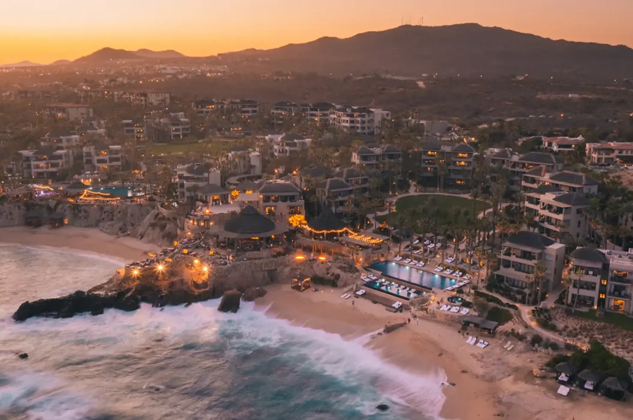 Aerial sunset view of Esperanza Cabo San Lucas beachfront and pools overlooking the Pacific Ocean
