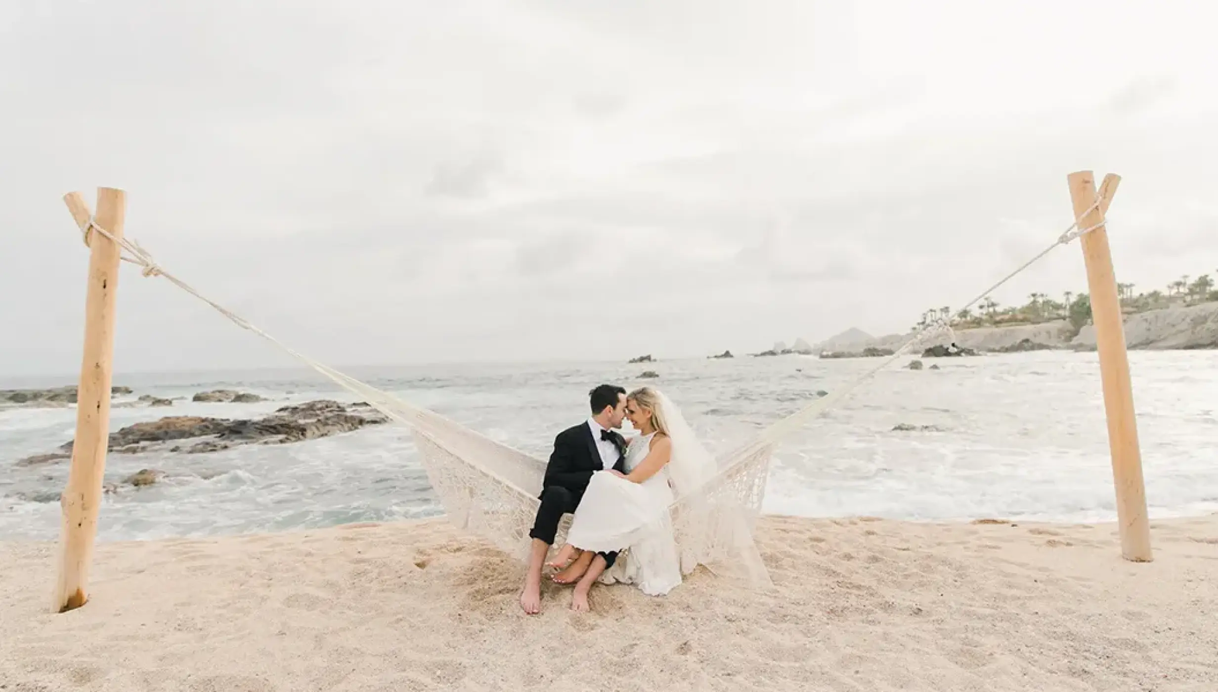 The bride and groom sitting in a beach hammock at Esperanza Cabo San Lucas