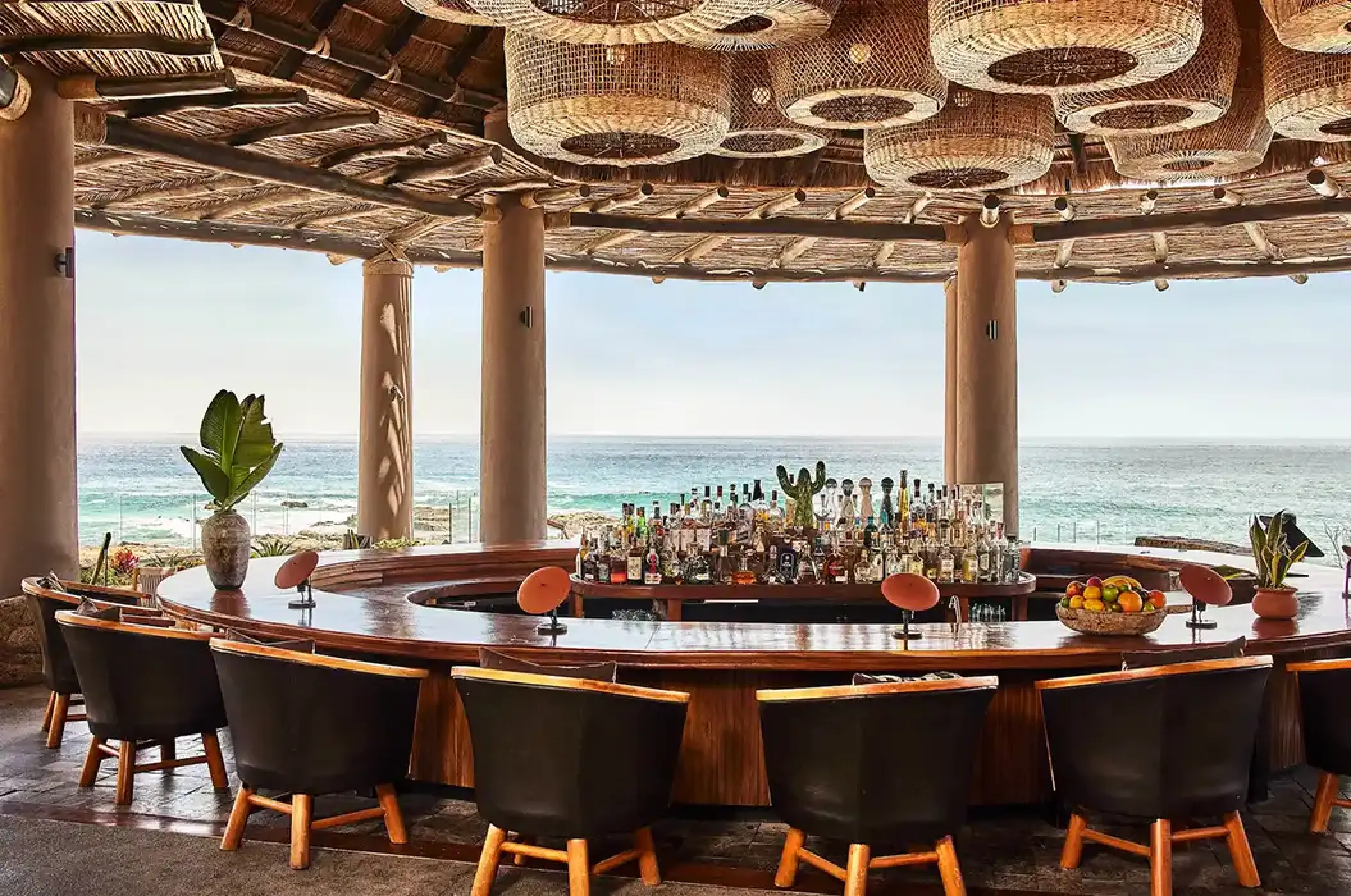 Open-air circular bar with ocean views and woven light fixtures at Esperanza, Cabo San Lucas