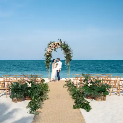 Beachfront wedding ceremony with a floral arch and wooden chairs at Excellence Coral Playa Mujeres, Cancun