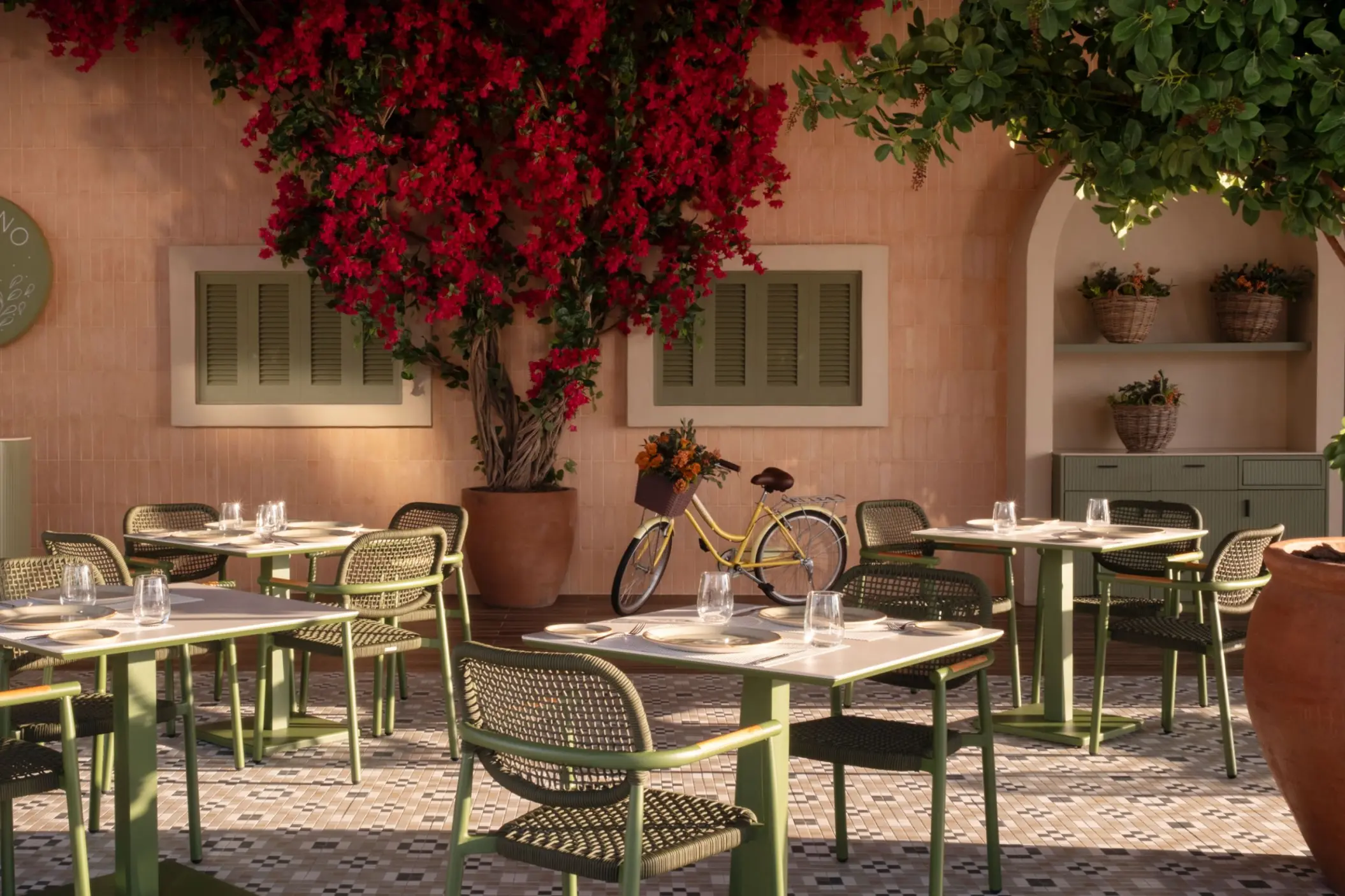 Oregano restaurant outdoor seating with red flowers and a vintage bicycle at Excellence Coral Playa Mujeres, Cancun