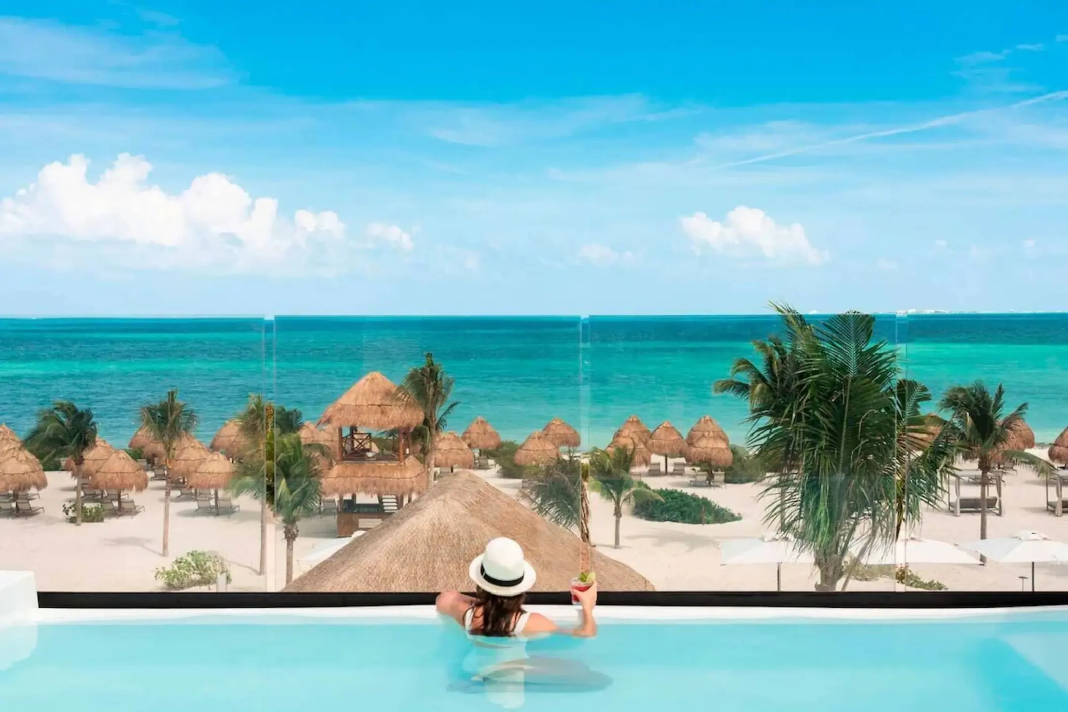 Woman in an infinity pool overlooking the beach at Excellence Coral Playa Mujeres, Cancun