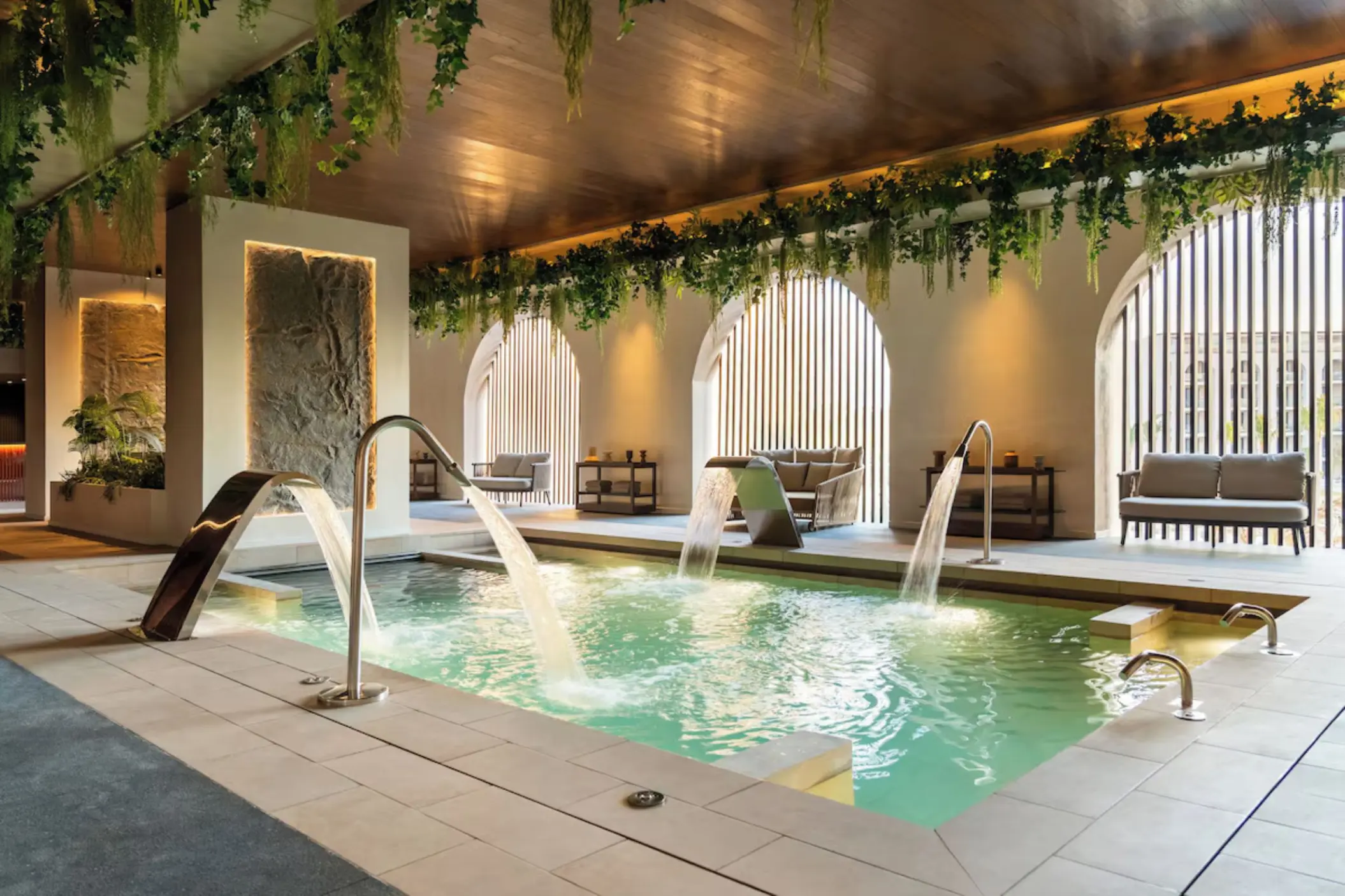 Indoor spa pool with hydrotherapy fountains and hanging plants at Excellence Coral Playa Mujeres, Cancun