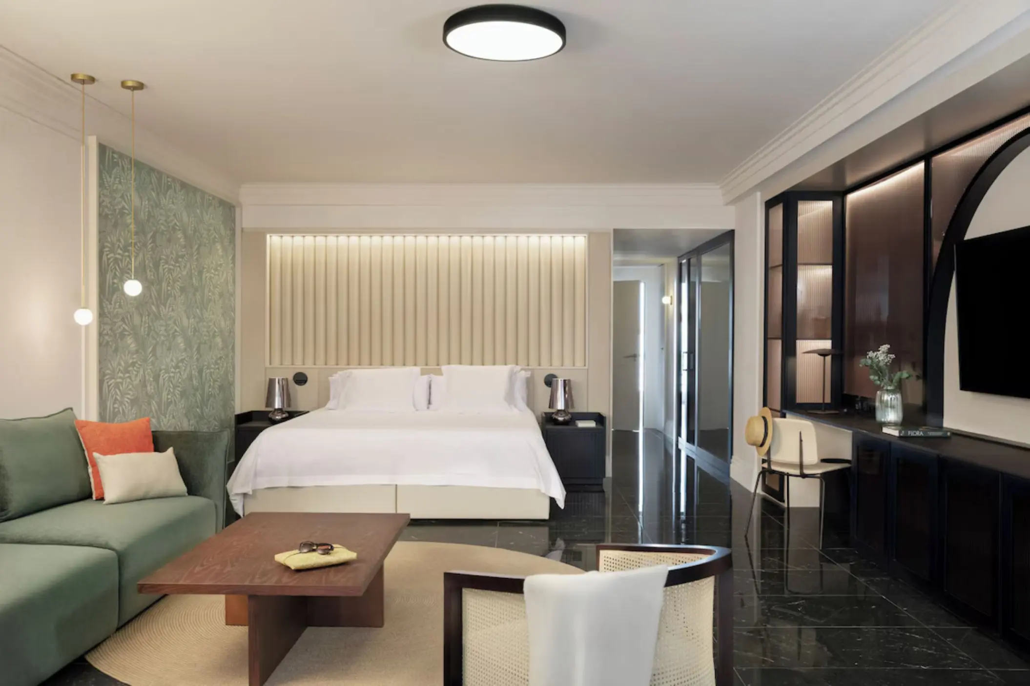 Modern guest suite with a king bed and green sofa at Excellence Coral Playa Mujeres, Cancun