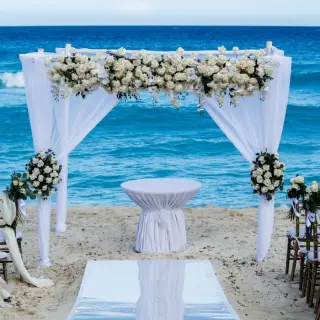 Beachfront wedding ceremony setup with white floral arch at Fiesta Americana Condesa, Cancun