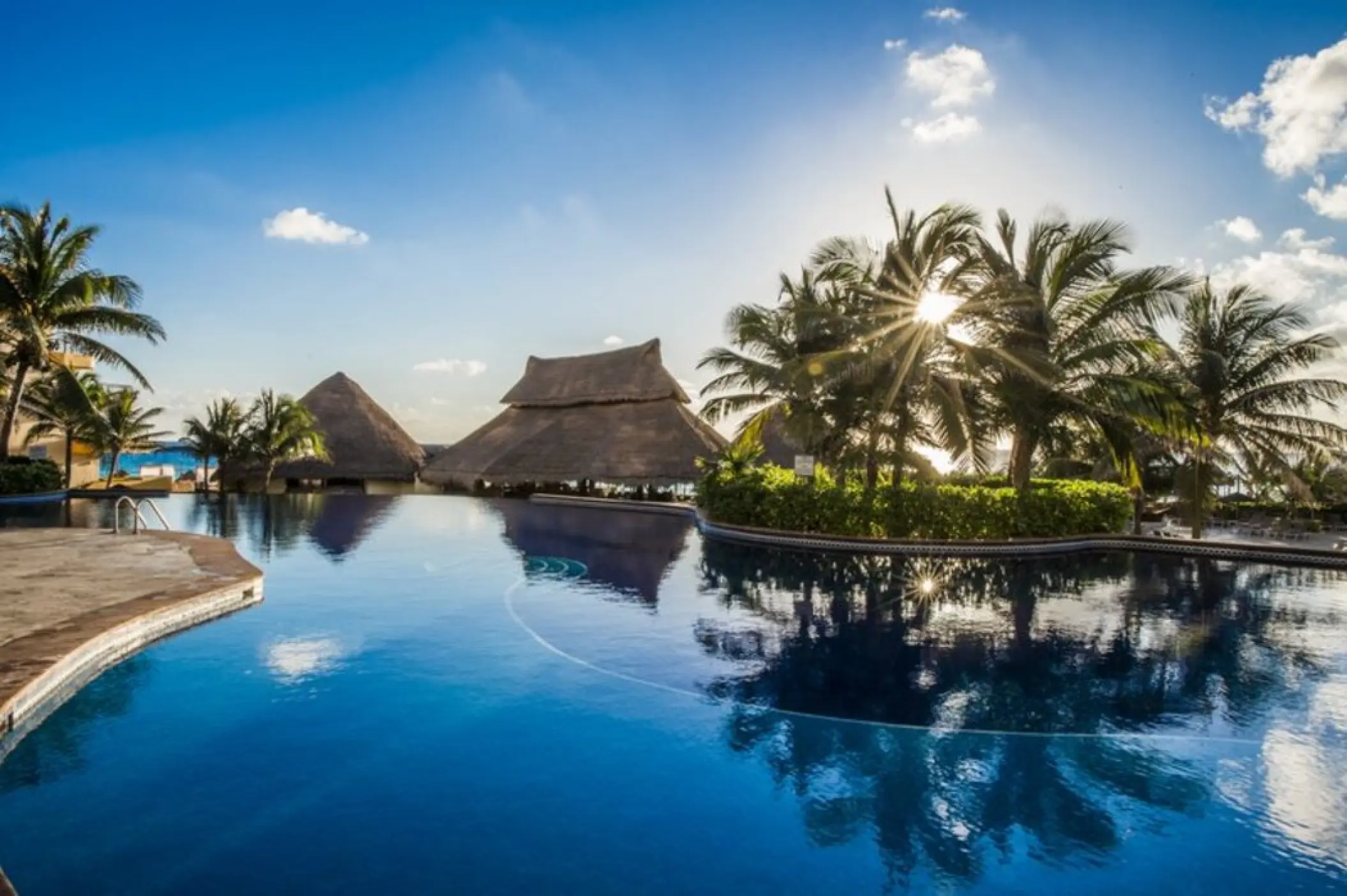 Fiesta Americana Condesa pool area with palm trees and thatched-roof palapas, Cancun