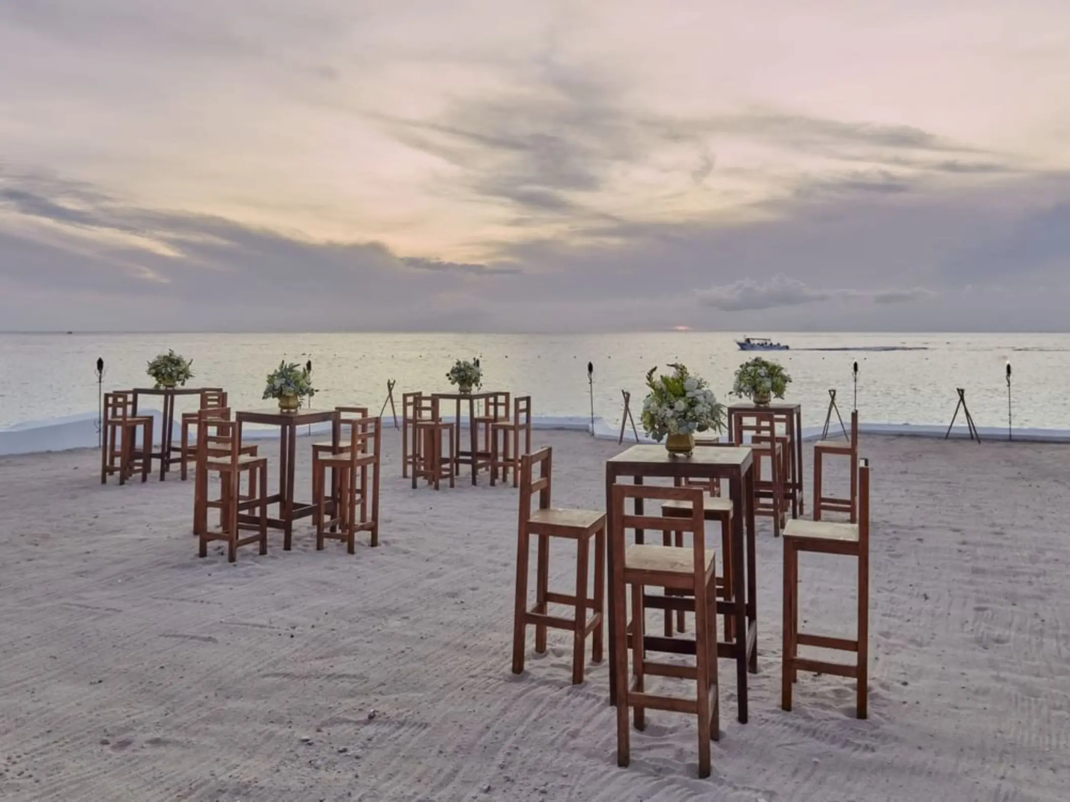Beach club wedding reception setup with wooden high-top tables at Fiesta Americana Cozumel
